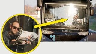 Автономен електрически автобус се движи по пътя, докато шофьорът чете вестник