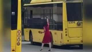 Шофьорка на тролейбус, облечена в червена рокля и обувки на висок ток, ремонтира машината